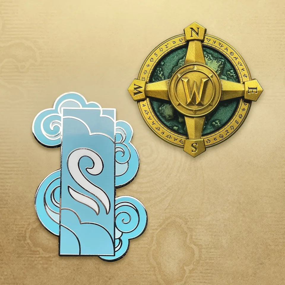 Zwei Anstecker: eine goldene Kompassrose mit W in der Mitte und ein hellblaues Wolkenbanner